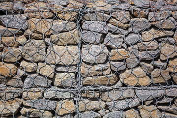 Stone wall in a metal grid as a background