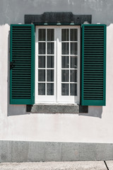 Fototapeta na wymiar Ornamental facade of colorful house in Sao Miguel, Azores. Portugal. Beautiful old tiny houses, green doors and window shutters