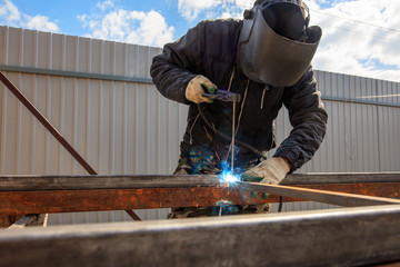 Welder welds metal at the construction site