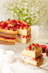Homemade strawberry cake on a glass stand on the white background.