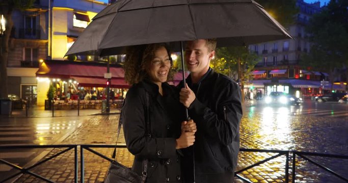 Millennial Couple Get Caught In The Rain On Paris Street, Multiethnic Male And Female Take Cover Under Umbrella Together On Rainy Evening, 4k