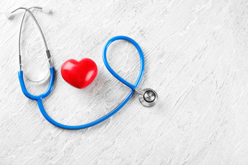 Stethoscope with red heart on wooden background. Health care concept
