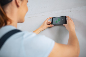 Great renovations. Female professional builder using her gadget while renovating a house