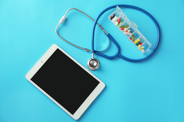 Stethoscope with tablet and pills on color background. Health care concept