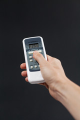 Hand using a remote control to activating air conditioning  on the dark background