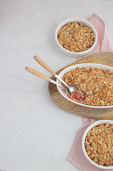 Strawberry and rhubarb homemade granola crumble with top view on white concrete background, copy space