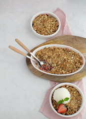 Strawberry and rhubarb homemade granola crumble with ice-cream top view on white concrete background, copy space