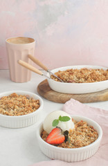 Strawberry and rhubarb homemade granola crumble with ice-cream and cup of coffee on the background, soft pink colors, vertical, selective focus
