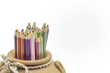 Close up colorful pencils in pottery vase  on white background with copy space.