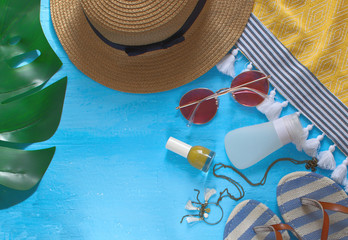 Summer holidays female accessories flat lay with hat, monstera leaf, sunglasses, flip flops, necklace, cream, nail polish and beach towel