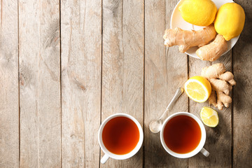 Fototapeta na wymiar Cups of hot aromatic tea with lemon and ginger on wooden table
