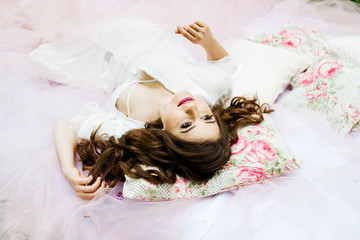 A pretty woman lays on a pink bed in the forest