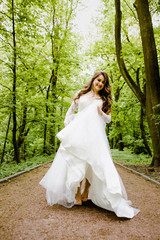 Obraz na płótnie Canvas An emotional girl in a white dress walks along the path in the park