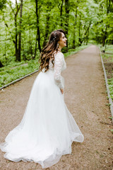 Obraz na płótnie Canvas An emotional girl in a white dress walks along the path in the park