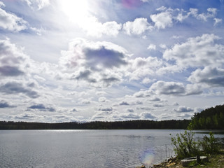 Summer landscape: blue lake on a Sunny day and sky with feathery clouds