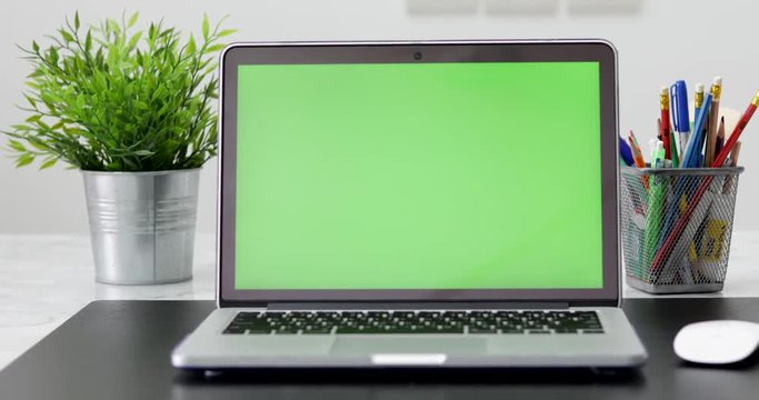 4K : A laptop computer with a key green screen set on work office table. Dolly in
