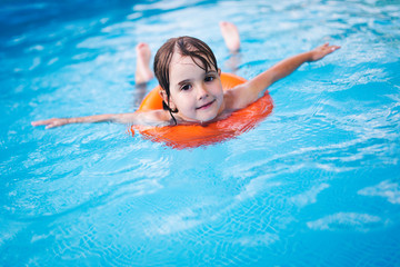 Fototapeta na wymiar Little girl in swimming pool with float ring