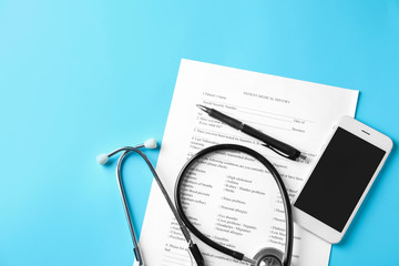 Stethoscope with patient medical history and phone on color background. Health care concept