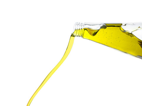 Pouring of olive oil from glass bottle on white background