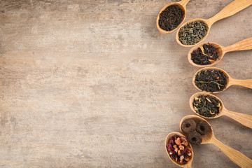 Different sorts of tea in spoons on light background, flat lay