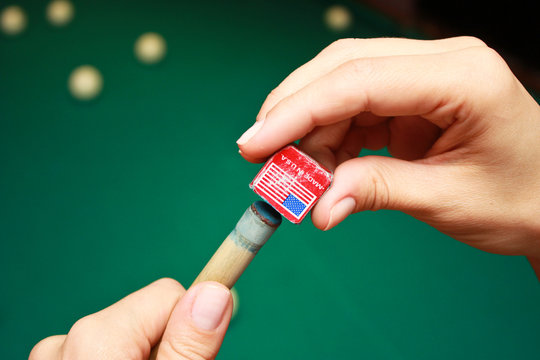 Billiard player rubs chalk his cue. Details of the game of billiards.