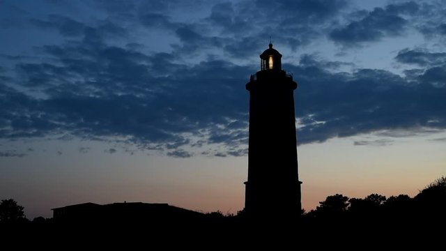 Flashing lighthouse just after sunset with clouds in the sky above. Location Morups Tange lighthouse outside Falkenberg, Sweden.