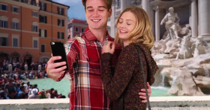 Happy young couple taking fun selfies in front of the Trevi Fountain, Male and female on vacation taking pictures for social media, 4k