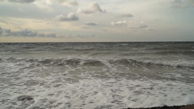 The sea with small waves near the shore in the early morning before dawn in cloudy weather.