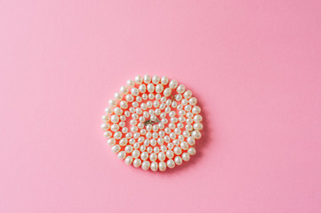 Wedding or fashion concept. Pearl necklace on a pink background.