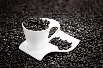white cup of coffee with coffee beans on a background of coffee beans