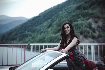 Fashion portrait of young woman in elegant dress outdoor in cabriolet car