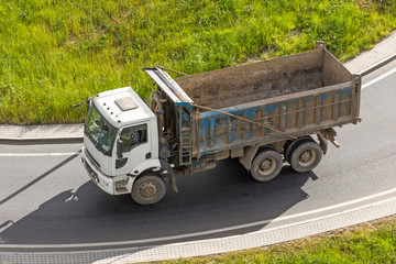 Truck dump from the body for cargo on the highway rides along the asphalt, top view.