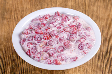 Fresh, ripe, forest strawberries with sour cream and honey in white plate, wild berry. Red strawberries background