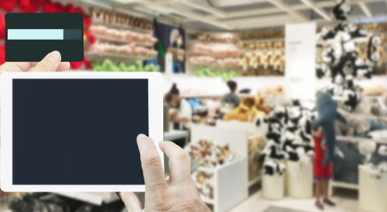 Obraz premium Hand hold tablet with credit card for shopping online business at the children toy shop background.