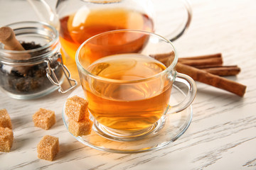 Glass cup of tasty tea on white wooden table
