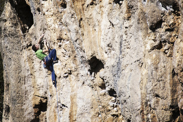 Man rock climber. Rock climber climbs on a rocky wall. Man makes hard move.