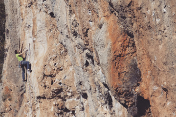 Man rock climber. Rock climber climbs on a rocky wall. Man makes hard move.