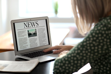 Mature woman reading news on laptop screen in cafe