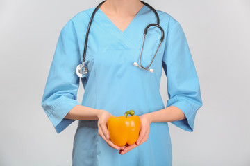 Female doctor with fresh pepper on white background