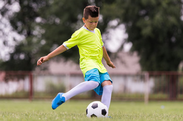 Boy kicking football on the sports field