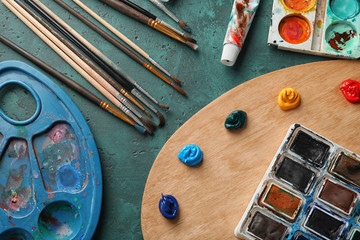 Paint palettes with brushes on table