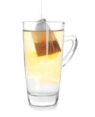 Brewing of hot beverage with tea bag in glass cup on white background