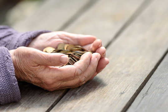 Money, coins, the grandmother on pension and the concept of life, minimum - hands of the old woman to hold a handful of coins on a wooden table
