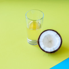 Half of coconut and coconut water on duotone background.