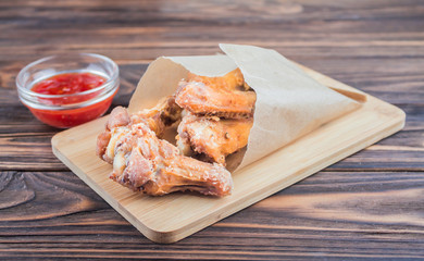 deep-fried chicken wings with tomato sauce, on a wooden background