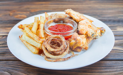 deep-fried chicken wings, French fries and onions, with sauce on a plate