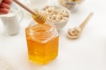 Pouring aromatic honey into jar, closeup