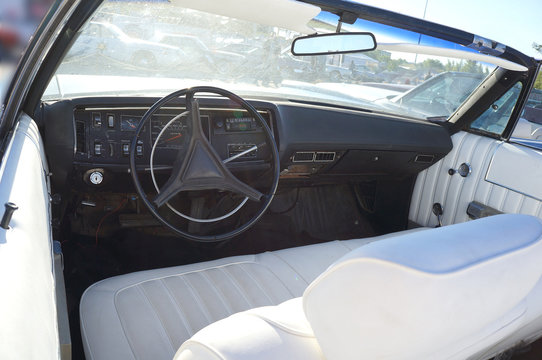 Fragment retro car dashboard.  White leather and black steering wheel.