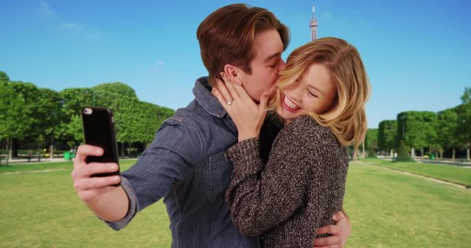 Newly engaged couple taking a selfie in front of the Eiffel Tower, Joyful male and female taking a picture to share good news with friends and family, 4k