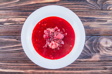 Ukrainian borscht in a plate on a wooden background